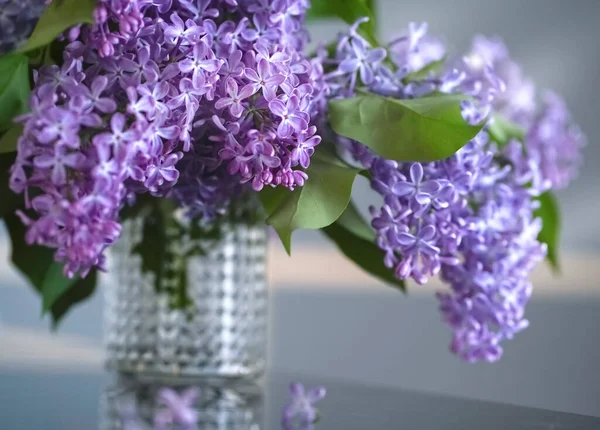 一束紫丁香放在透明花瓶里的桌子上 — 图库照片
