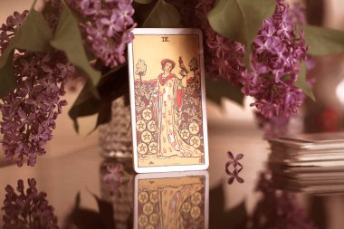Tarot cards on the table, Nine of Coins Pentacles. Lilac bouquet.  clipart