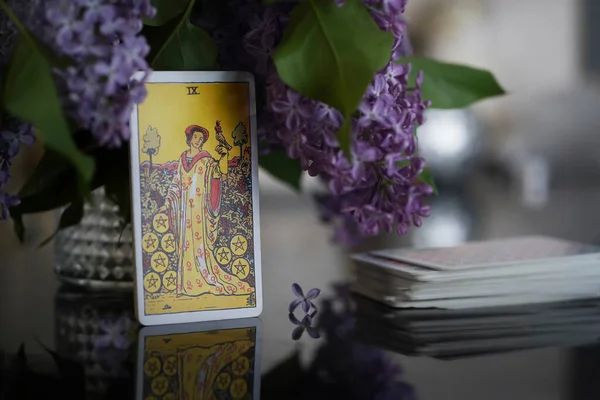 Masada Tarot kartları var, Bozuk Paraların Dokuzlusu. Leylak buketi. 