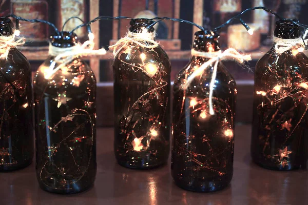 Vrolijk kerstfeest wenskaart. Garland brandt in donkere glazen flessen — Stockfoto