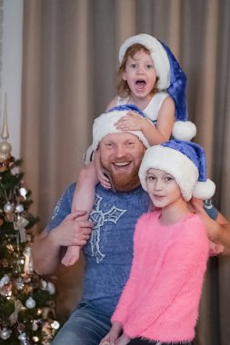 Mavi yılbaşı şapkalı kızları olan baba Noel 'i kutluyor.