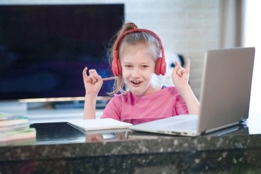 Mutlu genç kızın seçilmiş odak noktası kulaklık takmak webinar dinlemek çevrimiçi kurs konferans video çağrısı ile iletişim kurmak ve öğretmenlik dersiyle öğrenmek evde dizüstü bilgisayara bakmak.