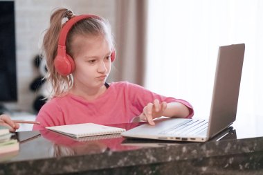 Mutlu genç kızın seçilmiş odak noktası kulaklık takmak webinar dinlemek çevrimiçi kurs konferans video çağrısı ile iletişim kurmak ve öğretmenlik dersiyle öğrenmek evde dizüstü bilgisayara bakmak.
