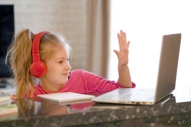 Mutlu genç kızın seçilmiş odak noktası kulaklık takmak webinar dinlemek çevrimiçi kurs konferans video çağrısı ile iletişim kurmak ve öğretmenlik dersiyle öğrenmek evde dizüstü bilgisayara bakmak.