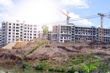 Vinçleri ve mavi gökyüzü arka planlı binaları olan bir sürü kule inşaat alanını bulanıklaştırmış. Yüksek kalite fotoğraf