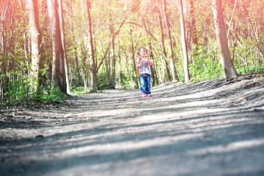 Sırt çantalı bulanık bir kız yolda scooter sürüyor.