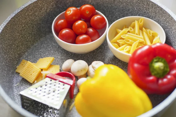 Blurred food composition of pasta, different ingredients in a skillet