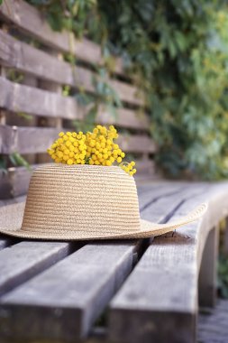 Hasır şapkalı yaz kompozisyonu, tahta arka planda momoza, dikey. Yüksek kalite fotoğraf