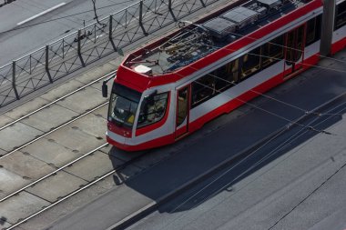 Kentsel kırmızı modern tramvay tren yolu boyunca ilerliyor. Vatandaşların ekolojik ve sosyal ulaşımı
