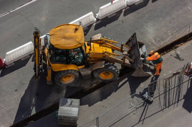 Şehrin sokaklarında yol yapımı için ağır bir yük kamyonu ve kova kullanarak onarım işi. Yol çalışması için inşaat sahası - üst görünüm. Kamu işleri, inşaat mühendisliği, yol inşaatı.