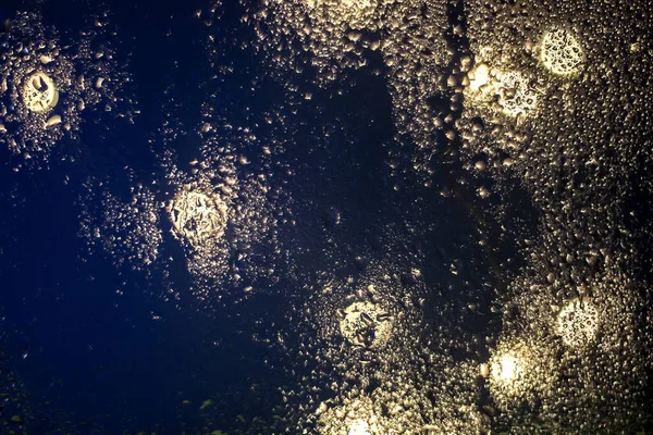 창유리에 떨어지는 물방울은 날씨에 도시의 조명을 원문의 — 스톡 사진