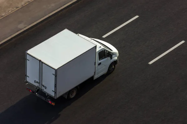 White new cargo van drives on city highway road without people and cars