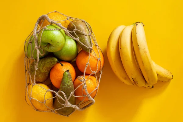 Zero waste concept - environmental care. String bag with fruit on a yellow background. No retouching.