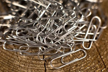 Ahşap arka planda birkaç ataç var. Eğitim veya iş için metal kırtasiye araçları.  