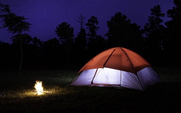 Маленький костер рядом с зажженной палаткой со звездами в небе над
