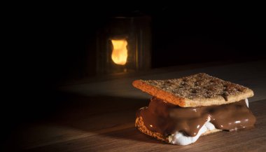 Kamp fener arkasında bir smore ile ahşap bir masa üstüne yaktı