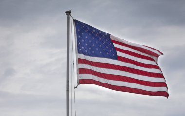 Bulutların arkasına rüzgarda hareketli bir Amerikan bayrağı