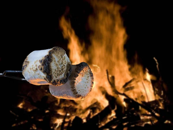 Two marshmallows being roasted over a campfire to make smores