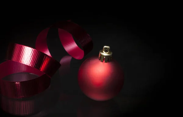 Red Christmas ornament and ribbon on a black background