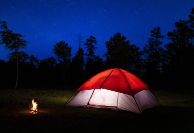 Yıldızlar ve küçük bir kamp ateşi ile yanan bir çadır içinde bir alan