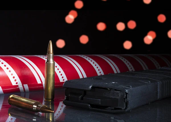 Rifle cartridges and magazine with Christmas wrapping paper and lights behind