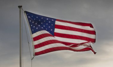 Sert bir esinti ve bulutların arkasına alacakaranlıkta Amerikan bayrağı