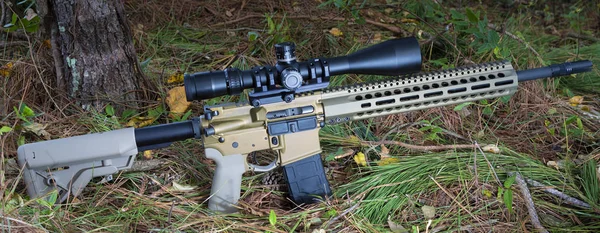 AR-15 with rifle scope that is on the forest floor