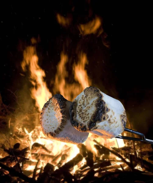 Two marshmallows being roasted over a campfire to make smores