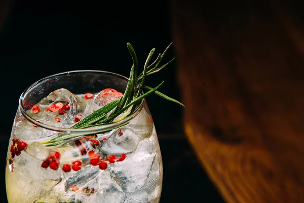 Taze biberiye ve pembe biberiyelerle süslenmiş cin ve tonik kokteylin yakın plan çekimi canlandırıcı ve ferahlatıcı bir içecek oluşturur.