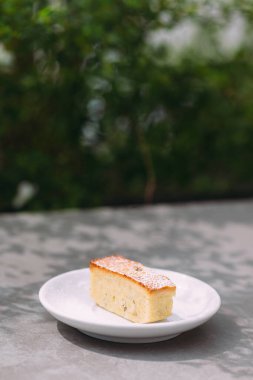 Pound cake with powdered sugar on white plate. Sweet food outdoor. Delicious dessert with natural light