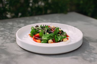 Plated salad with fresh greens, cooked chickpeas, and bell pepper, offering a healthy and gourmet dining experience