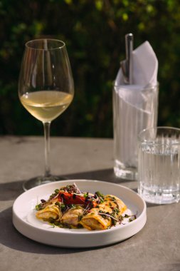 Savory crepes presenting a culinary concept of fine dining. Serving as a gourmet meal with white wine in a restaurant setting