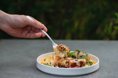 Ağzına kadar yaratıcı gurme yemekleriyle dolu bir çatalı tutarak, güzel bir yemek ve lezzetli bir yemeğin zevkini resmediyor.