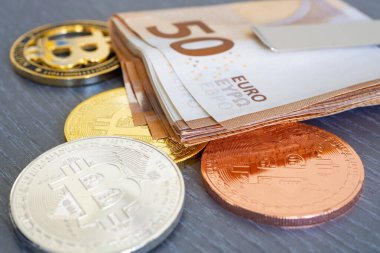 Gri ahşap dokuma masa zemininde altın, gümüş ve bronz bir bitcoin üzerinde 50 avroluk banknotların yakın plan çekimi. Şifreleme para birimi için kavramsal resim - BTC.