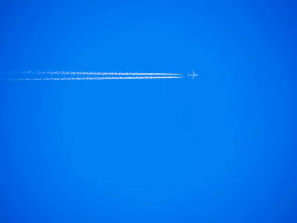 航空機エンジンからの排気ガスの痕跡 真っ青な空に白い縞模様と飛行機 白い結露トラックと現代のジェット飛行機 旅行のコンセプト 美しい背景や壁紙 — ストック写真
