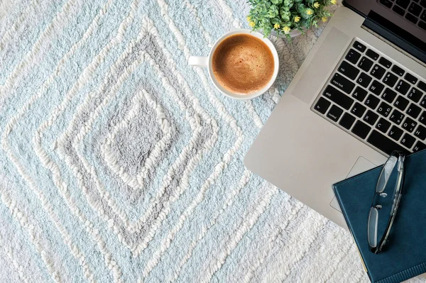 Top view laptop with book and cup of coffee on white carpet or rug, copy space.