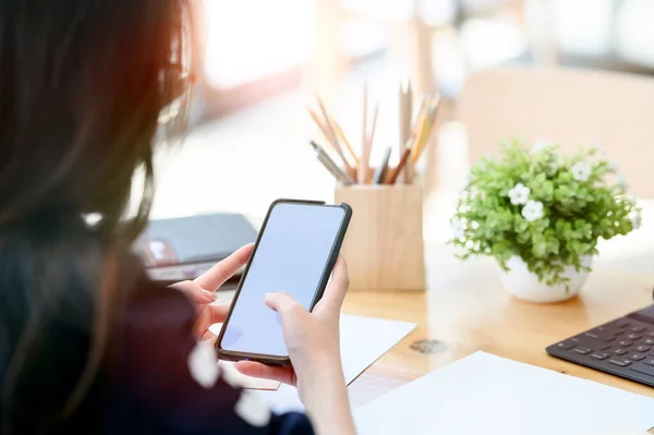 Ofiste cep telefonu kullanan genç bir iş kadını..