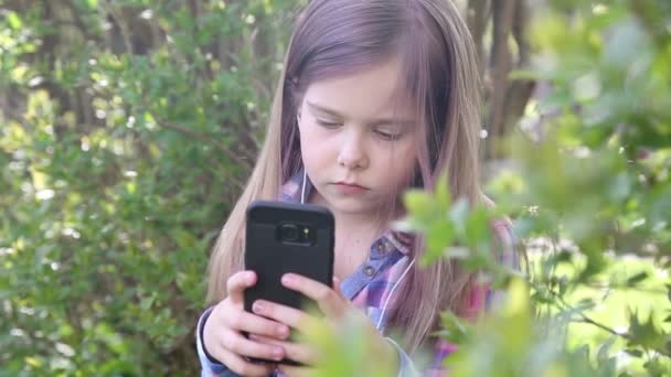 Chica jugando en el teléfono y escuchando música en los auriculares — Vídeo de stock