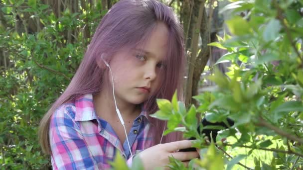 Chica jugando en el teléfono y escuchando música en los auriculares — Vídeos de Stock