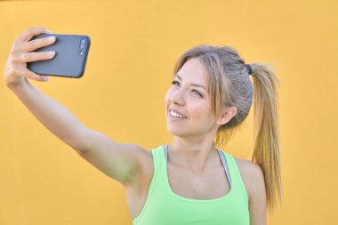 Güzel sarışın kız cep telefonuyla selfie çekiyor..