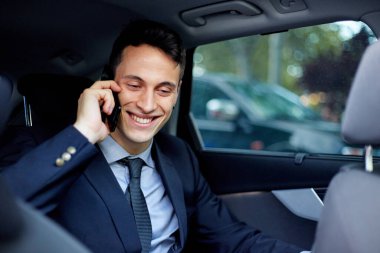 Kiralık bir arabada seyahat ederken iş adamı cep telefonuyla konuşuyor.