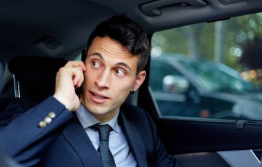 Kiralık bir arabada seyahat ederken iş adamı cep telefonuyla konuşuyor.