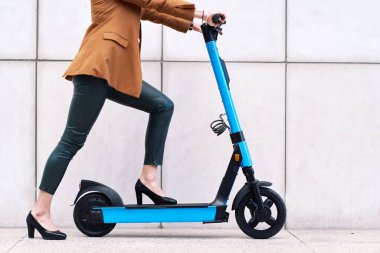 Şehirde elektrikli scooter kullanan genç bir kadın.