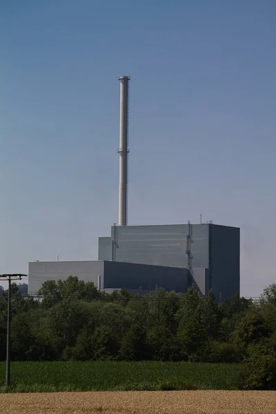 The machine house with the steam turbines of a nuclear power plant. And behind it a chimney.