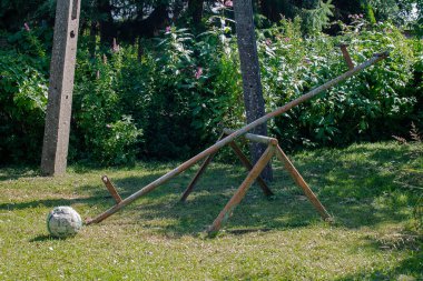 Güneşli bir günde terk edilmiş oyun parkı. Kırık bir salıncak ve havasız bir futbol topu görebilirsiniz..