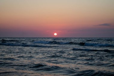 Deniz kenarında romantik bir gün batımı. Dalgaların üzerinde batan güneş.