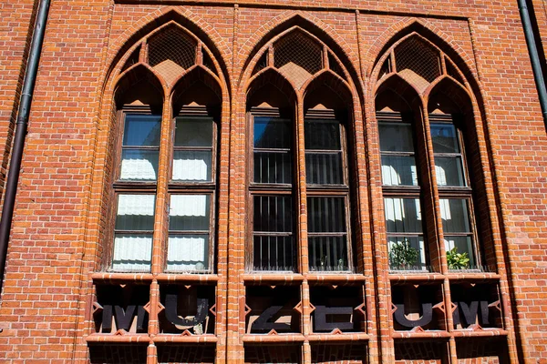 Three Gothic windows side by side in a brick facade