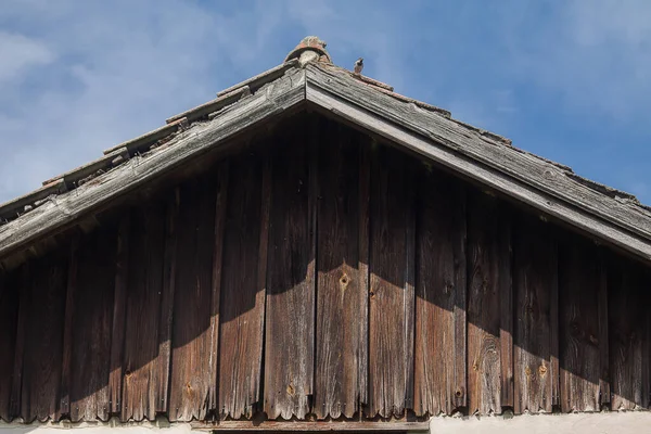 Ağaç kaplı ev geçidi. Çatı, doğanın güçleriyle işaretlenmiştir. Yaşını görebiliyorsun..
