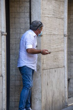 Teni, İtalya 27 Temmuz 2020: Medil maskeli ve akıllı telefonlu bir adam.
