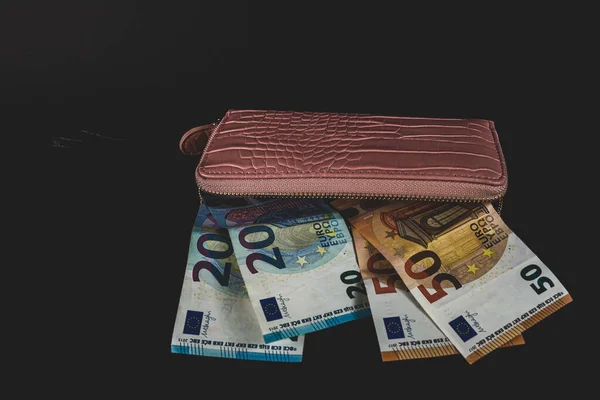 women's wallet on top of banknotes of different currency